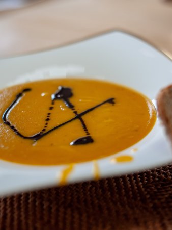 Rezept Foto von der Curry Kürbiscreme Suppe mit einer Scheibe Holzofenbrot vom Biobäcker Kellermann aus Amberg. Garniert mit Kürbiskernöl aus der Steiermark.