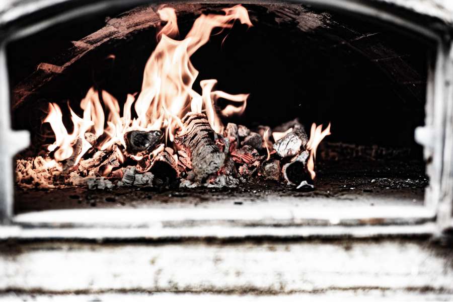Rezept Foto Holzofen Pizza Komplettanleitung. Beim Anschüren und nachschüren des Holfofens werden die Scheite und das Feuer von links nach rechts und später von vorne nach hinten verschoben. Das Bild zeigt das linksseitige Feuer, das richtig kräftig abbrennt.