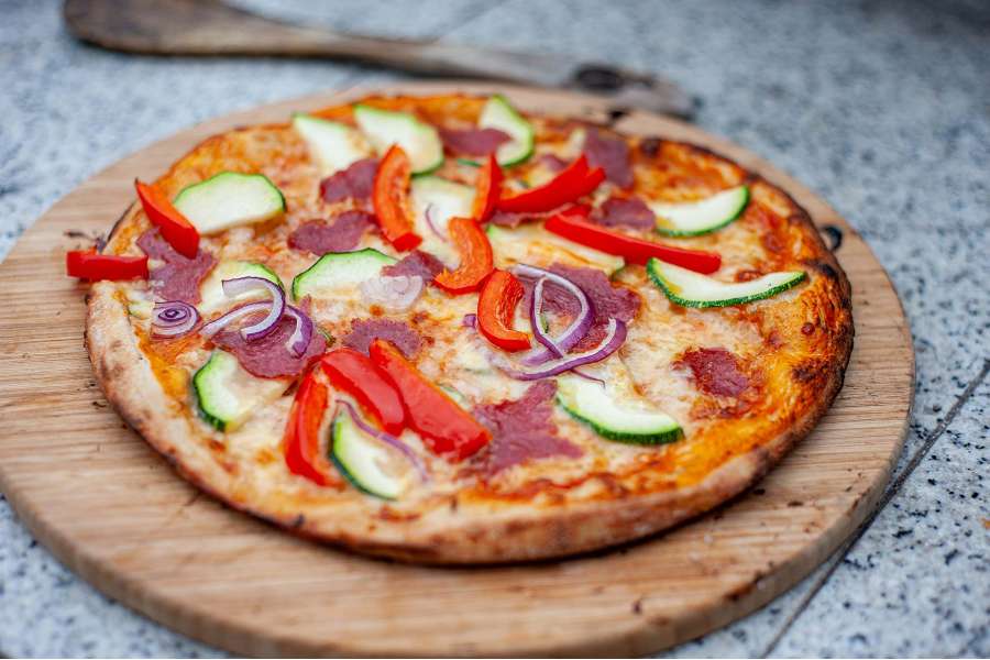 Rezept Foto Holzofen Pizza Komplettanleitung. Fertig gebackene Pizza mit Salami und frischem Gartengemüse.
