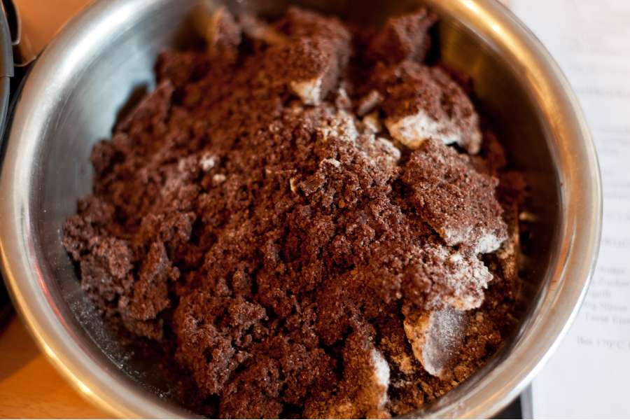 Rezept Foto Russischer Zupfkuchen. Die Kakao Masse und die Butter wurden zusammen mit dem Zucker in einer Schüssel vermengt. Es sind größere Klumpen entstanden, die als Streusel dienen.