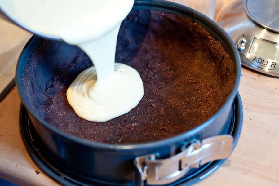 Rezept Foto Russischer Zupfkuchen. Die Vanillepudding Füllung wird gerade aus der Schüssel auf den Boden gekippt.