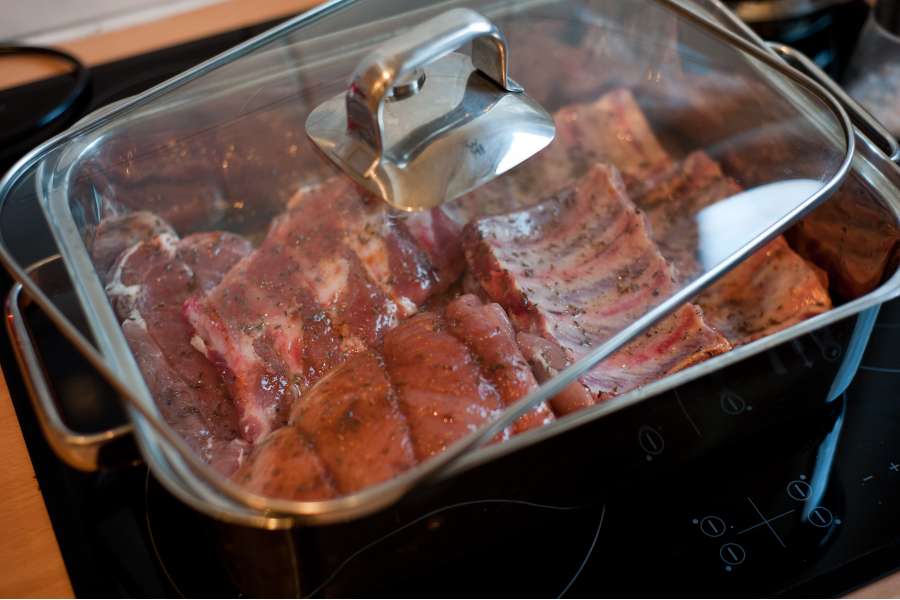 Rezept Foto Bayerischer Schweinebraten in der Kümmelbiersoße. Detailaufnahme von den Schweinerippchen ohne Knorpel die im Bräter bereitliegen und darauf warten im Ofen gebraten zu werden.