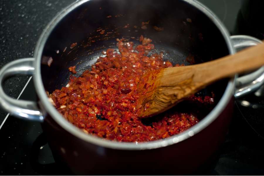 Rezept Foto BBQ Barbecue Bier Sauce. Die Zwiebel Stücke werden mit dem Tomatenmark und den Gewürzen in einem Topf scharf angebraten.