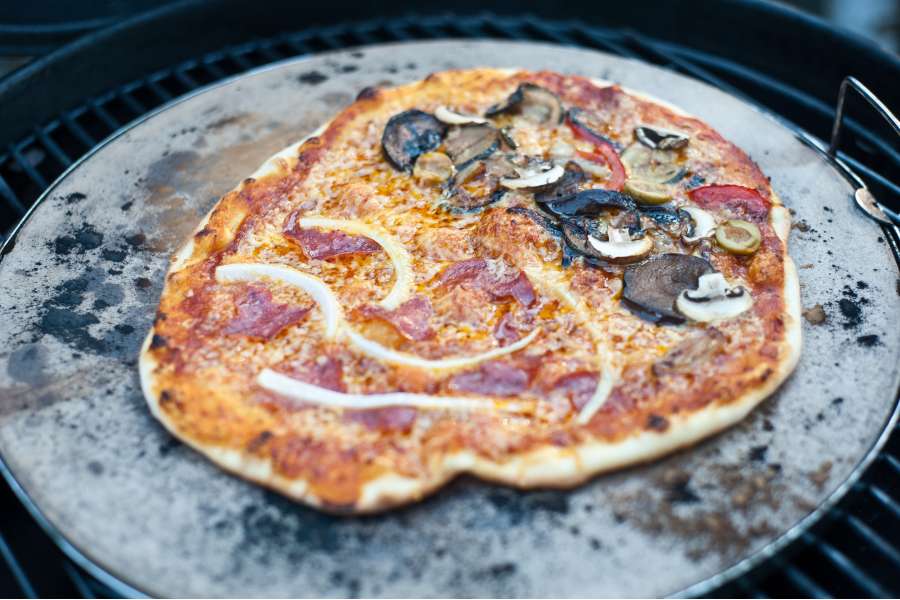 Rezept Foto Grillpizza und Ofenpizza Italien. Foto vom Grill und einer krossen Pizza die noch auf dem Backstein liegt.