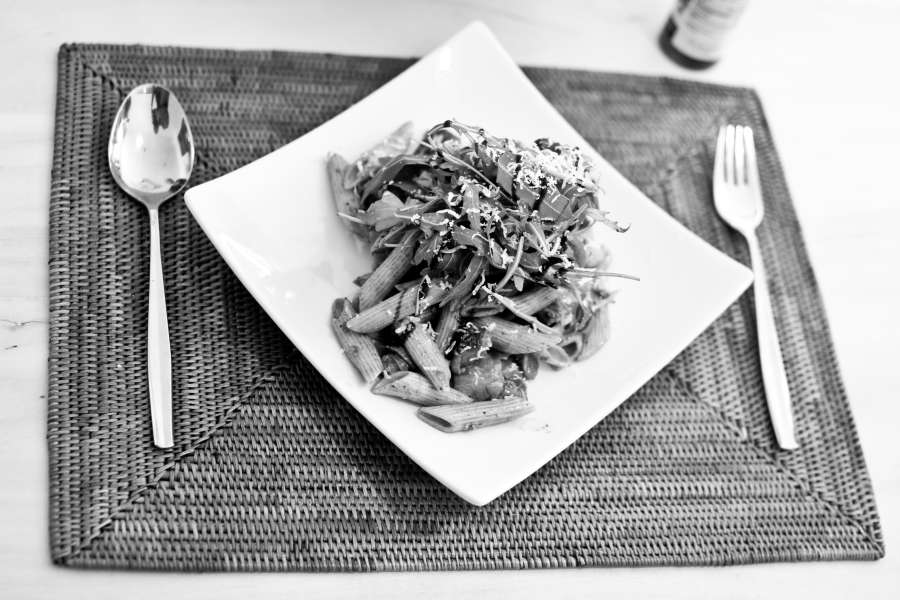 Rezept Foto Italienischer Nudelsalat. Der Antipasti Salat ist auf einem geschwungenem Teller angerichtet und mit Balsamico Essig beträufelt.