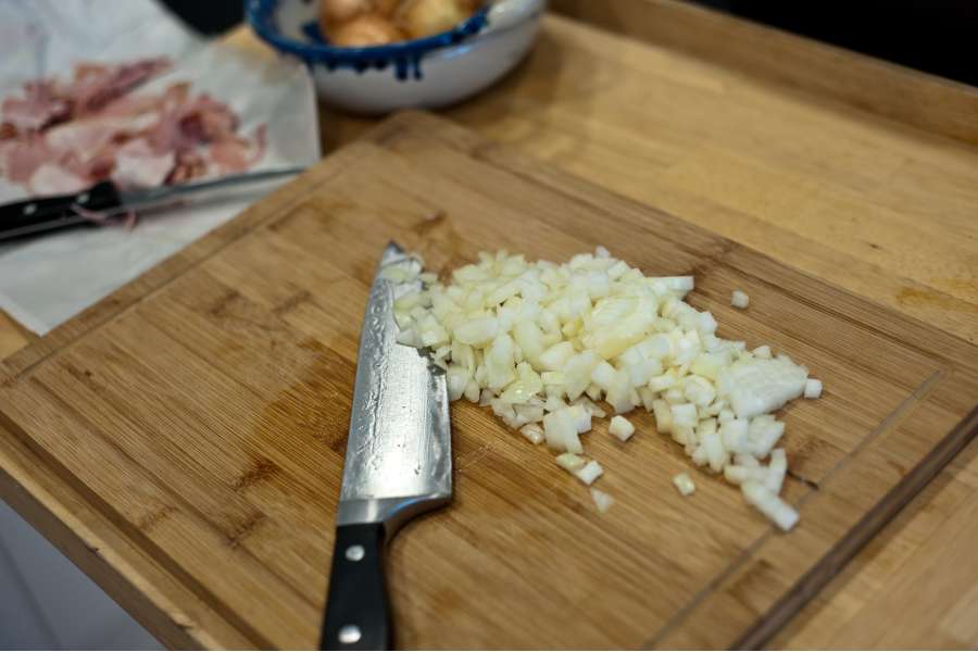 Rezept Foto Lasagne selber machen. Schneidebrett auf dem die Zwiebeln für die Lasagne fein gehackt wurden.
