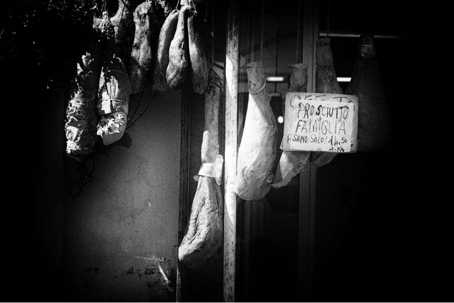 Rezept Foto Spaghetti Carbonara. Italienischer Metzger in einer kleinen Gasse in Anguillara. Die Parma Schinken hängen vor der Ladentür.