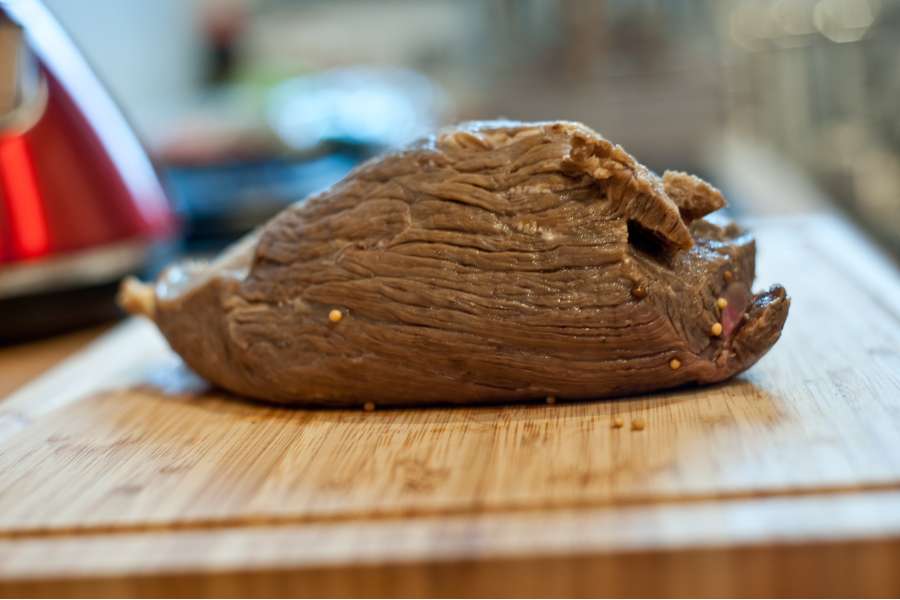 Rezept Foto Sauerbraten mit Serviettenknödel. Seitenansicht des 5 Tage lang gebeizten Sauerbratens. Er sieht von außen grau aus und von innen ist das Fleisch dunkelrot.